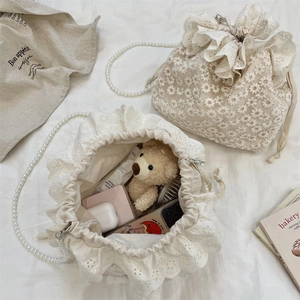 Detail der weißen Spitzen-Beuteltasche mit Perlenkette und Einblick in den Innenraum