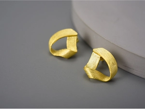 Detailed close-up of golden S925 silver twisted triangle hoop earring with brushed texture