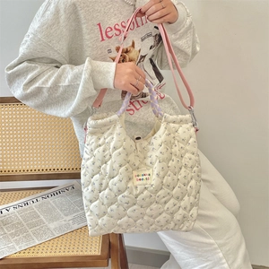 Close-up of quilted floral handbag with diamond stitching and adjustable pink strap