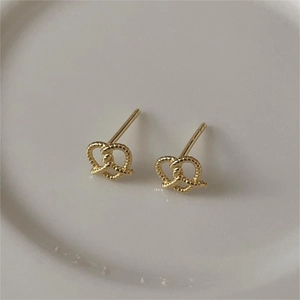 Minimalist gold pretzel twist knot stud earrings in 925 sterling silver on a ceramic tray