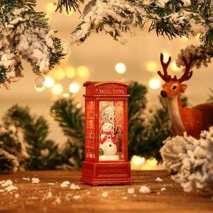 Close-up of lighted red telephone booth Christmas ornament with snowman landscape