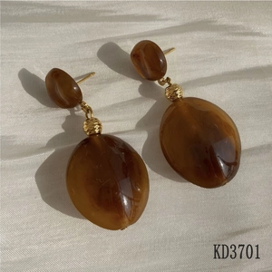 Macro view of vintage amber resin earrings with gold metallic spheres on white fabric