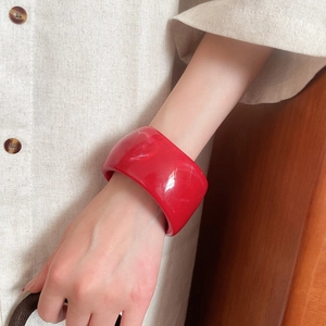 Detail of red marble-patterned resin wide bangle worn with a stylish linen shirt