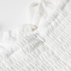 Détail de la robe longue blanche montrant la texture froncée et un zip invisible discret