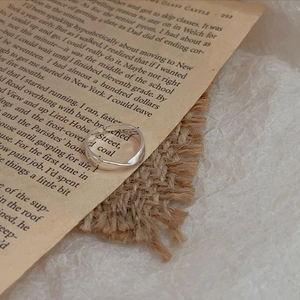 Detailed view of minimalist 925 silver twisted ring on vintage book pages and burlap