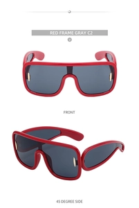Close-up of red oversized cycling sunglasses with gold hinge detail and gray lenses