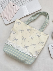 Blue bow canvas tote bag with lace trim and checkered pattern in a desktop setting