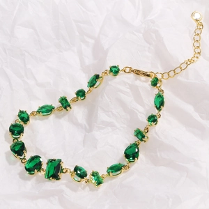 Detail of adjustable gold bracelet with emerald green crystals and lobster clasp
