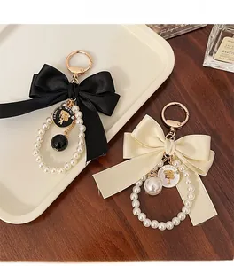 Detail of elegant black and cream bow keychains with pearls and gold fashion charms