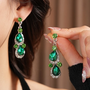 Macro detail of vintage emerald waterdrop earrings with silver crystal settings