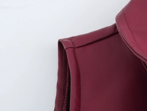 Close-up van de bordeauxrode PU-lederen halslijn en stikseldetails op de mouwloze jurk