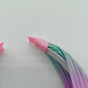 Dettaglio ravvicinato di cerchietto plissettato sfumato arcobaleno con bordo rosa