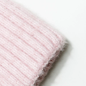 Vista macro dettagliata del cappello in maglia rosa morbida con texture pelosa e coste