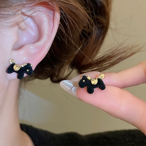 Close-up of black flocked puppy stud earrings featuring golden collar and ear details