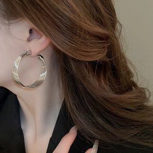 Close-up of silver multilayer C-shaped earrings on model with metallic finish