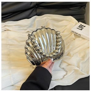 Detail of silver shell-shaped acrylic clutch with beaded handle and chain strap