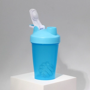 Blue transparent shaker bottle with mixing ball on a white display stand
