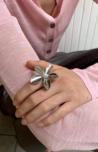 Detail of silver flower ring with white pearl center on model wearing pink knit