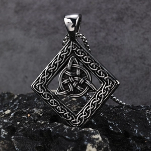 Pendentif Triquetra Viking en acier poli sur un fond de pierre minérale sombre
