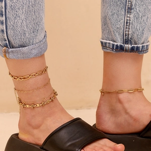 Detail of layered gold anklet with heart pendant and link chain on a female ankle
