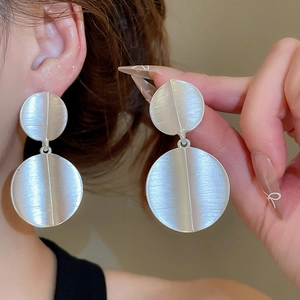Macro shot of large matte silver circular earrings with a brushed metal texture