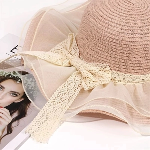 Detail of elegant straw sun hat with lace bow and pleated mesh brim in nude pink