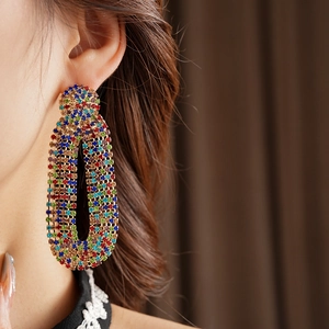 Detail of vintage gold oval earrings with colorful zircon stones on model's ear