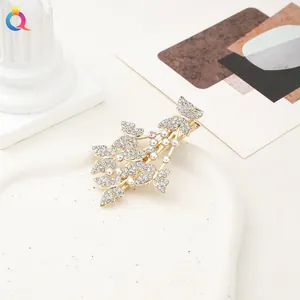 Macro shot of rhinestone-encrusted butterfly and leaf hair clip on white ceramic tray