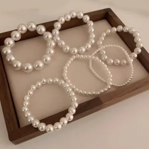 French vintage pearl stretch bracelet set with six varying sizes on a beige display tray