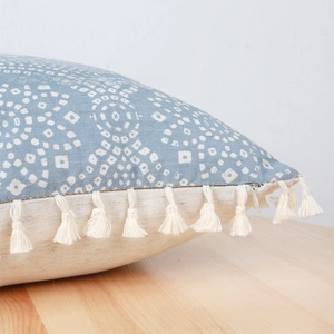 Detail of blue geometric floral cushion cover with decorative cream tassels and zipper