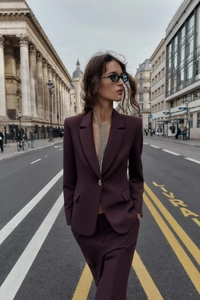 Détail d'un tailleur pantalon bordeaux avec chaîne à franges argentée dans la rue