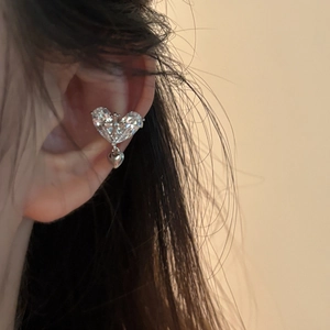 Close-up detail of a sparkling zircon heart ear cuff with central cross design in 18k gold plating