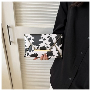 Close-up of cow print envelope clutch bag with elegant gold metal buckle detail