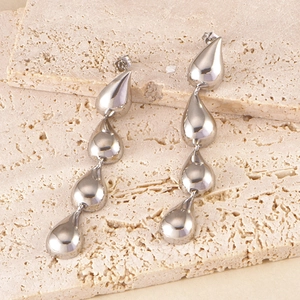 Macro shot of silver tiered teardrop dangle earrings on a textured stone surface