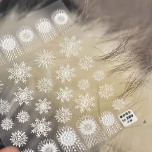 Detailed macro shot of white 3D embossed snowflake nail art stickers with relief texture