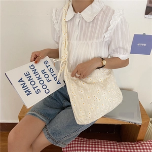 Daisy print tote bag styled with lace blouse and denim for a fresh, casual aesthetic