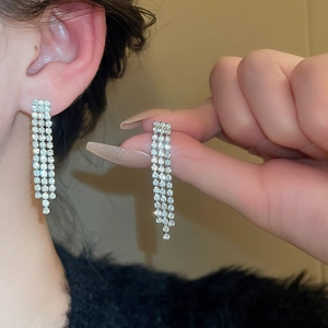 Detail view of silver three-row tassel rhinestone earrings worn for a luxury evening look
