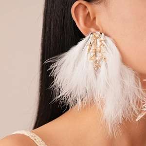 Détail de boucles d'oreilles en plumes blanches avec branches dorées et perles