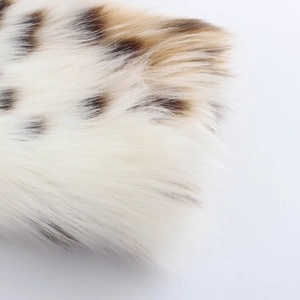 Detailed close-up of soft white faux fur fabric with brown leopard spots and long plush texture