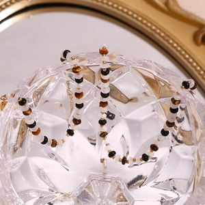 Detail of tiger eye and white bead necklace with gold spacers on crystal glass