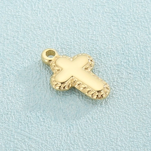 Gold stainless steel cross pendant with detailed woven textured edges on a blue background