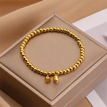 Macro shot of gold beaded bracelet featuring detailed lotus pod and bud charms