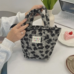 Detail of leopard print plush handbag with soft faux fur texture and top handle strap