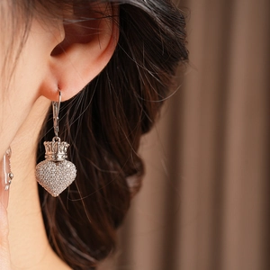 Gros plan d'un mannequin portant des boucles d'oreilles cœur couronne en argent