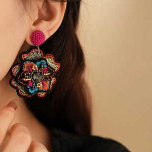 Detailed close-up of handmade embroidered flower earring with colorful beads and gray stone