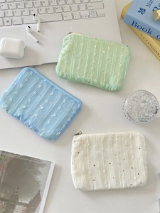 Three sequined chiffon floral coin purses in blue, green and beige on a white desk