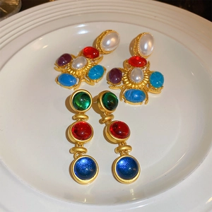 Vue détaillée de boucles d'oreilles baroques dorées avec perles et pierres colorées