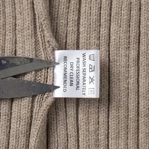 Detailed view of camel rib-knit fabric texture and white care label with washing symbols