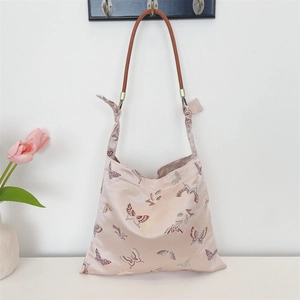 Close-up of pink satin hobo bag with butterfly patterns and brown rope handle details