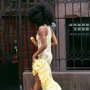 Détail de la robe sans manches en dentelle jaune montrant la texture et l'ourlet plissé